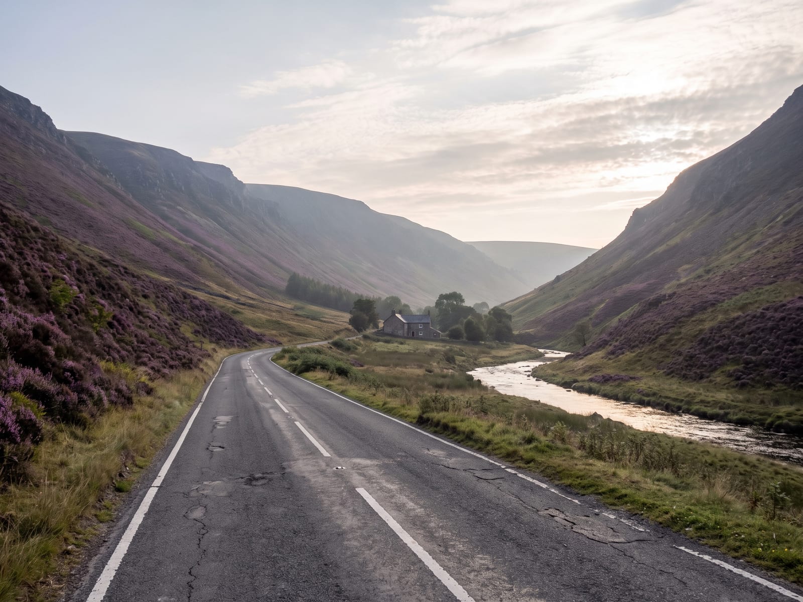 Near Abergavenny: a quiet tarmac road running along the foot of a steep heather-covered mountain ridge in the Black Mountains, Wales