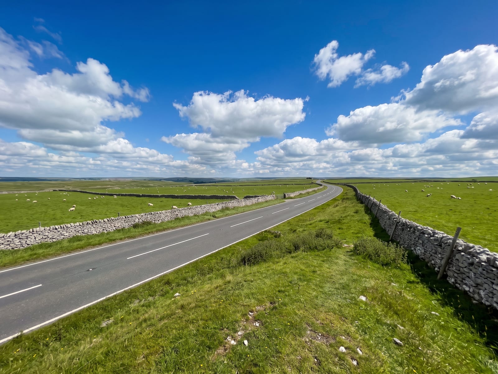 Near Ashbourne: a two-lane tarmac road crossing high limestone plateau farmland in the White Peak, Derbyshire