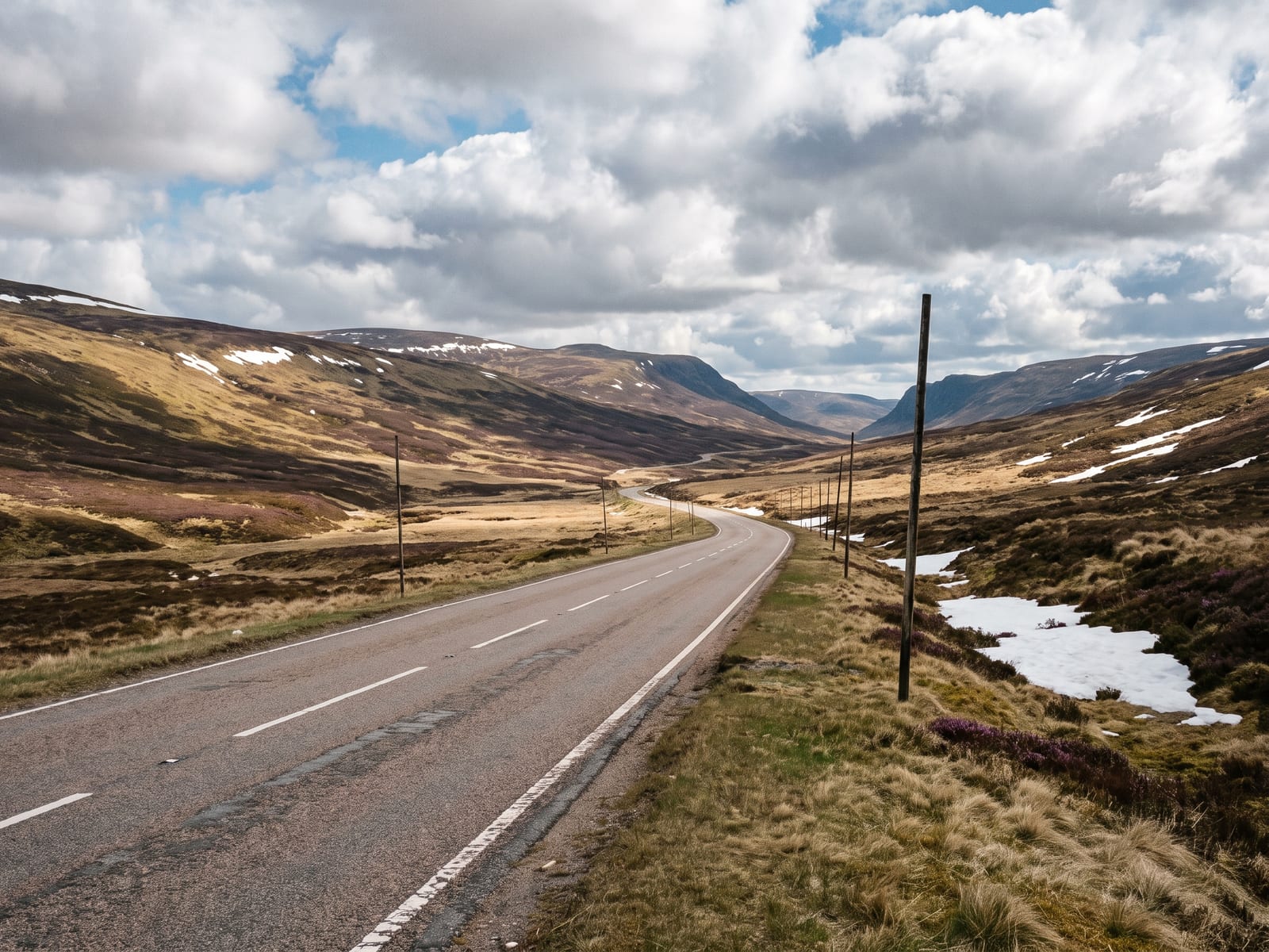 Near Blairgowrie: a wide tarmac road climbing across high open Highland moorland towards a pass in the Cairngorms, Scotland