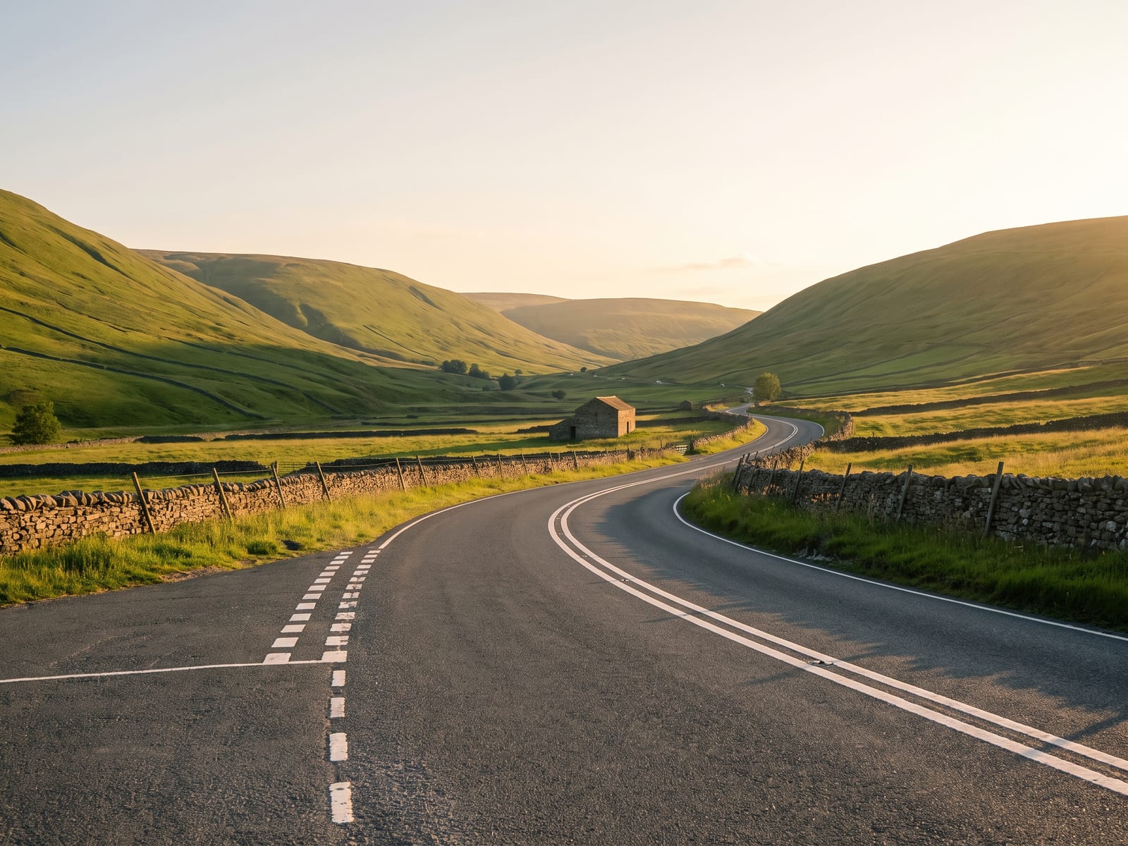 Near Kirkby Stephen: a two-lane tarmac road running along the floor of a broad upland valley in the northern Yorkshire Dales