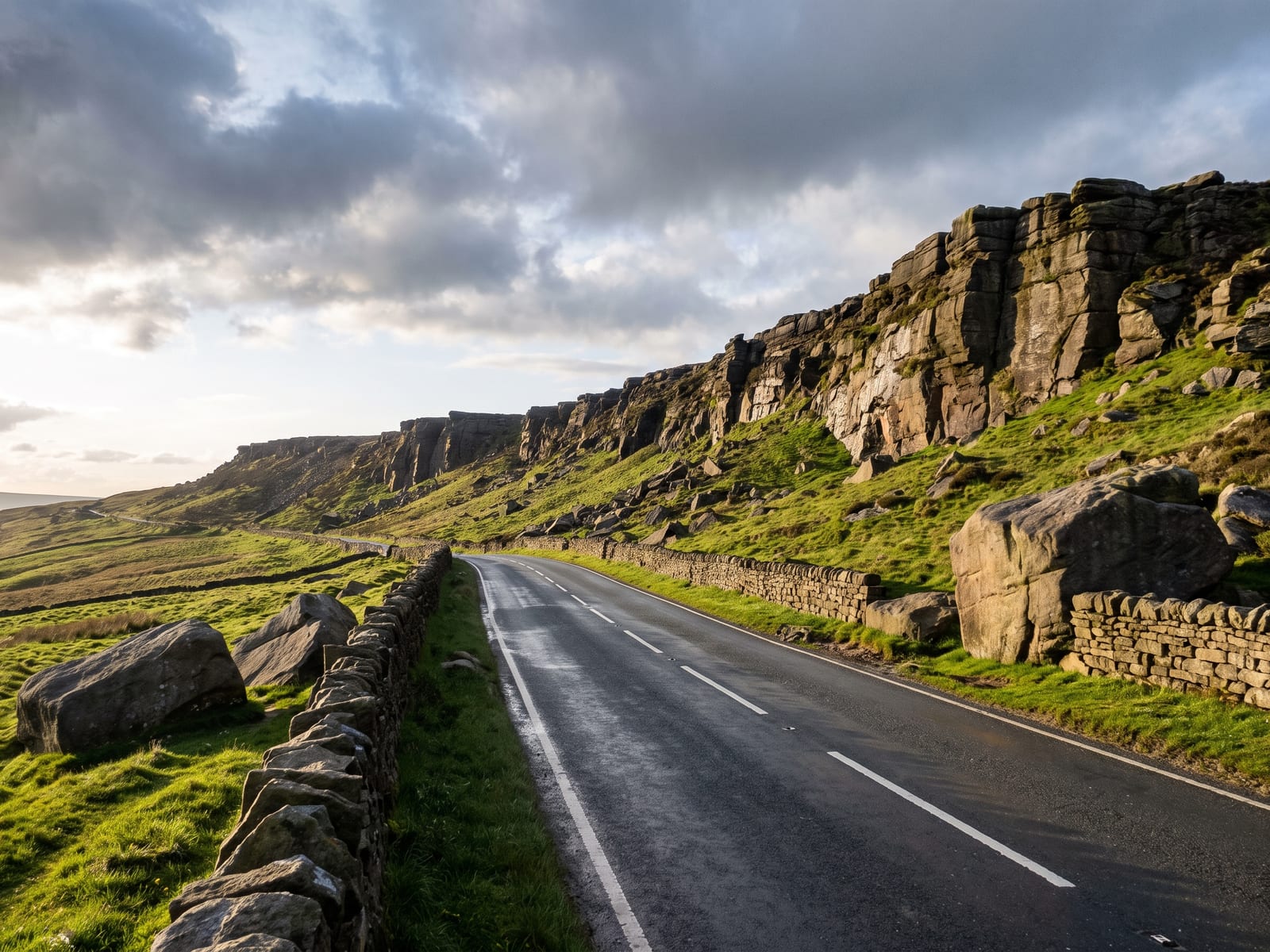 Near Leek: a quiet tarmac road crossing open Staffordshire Moorlands under a long rocky gritstone ridge