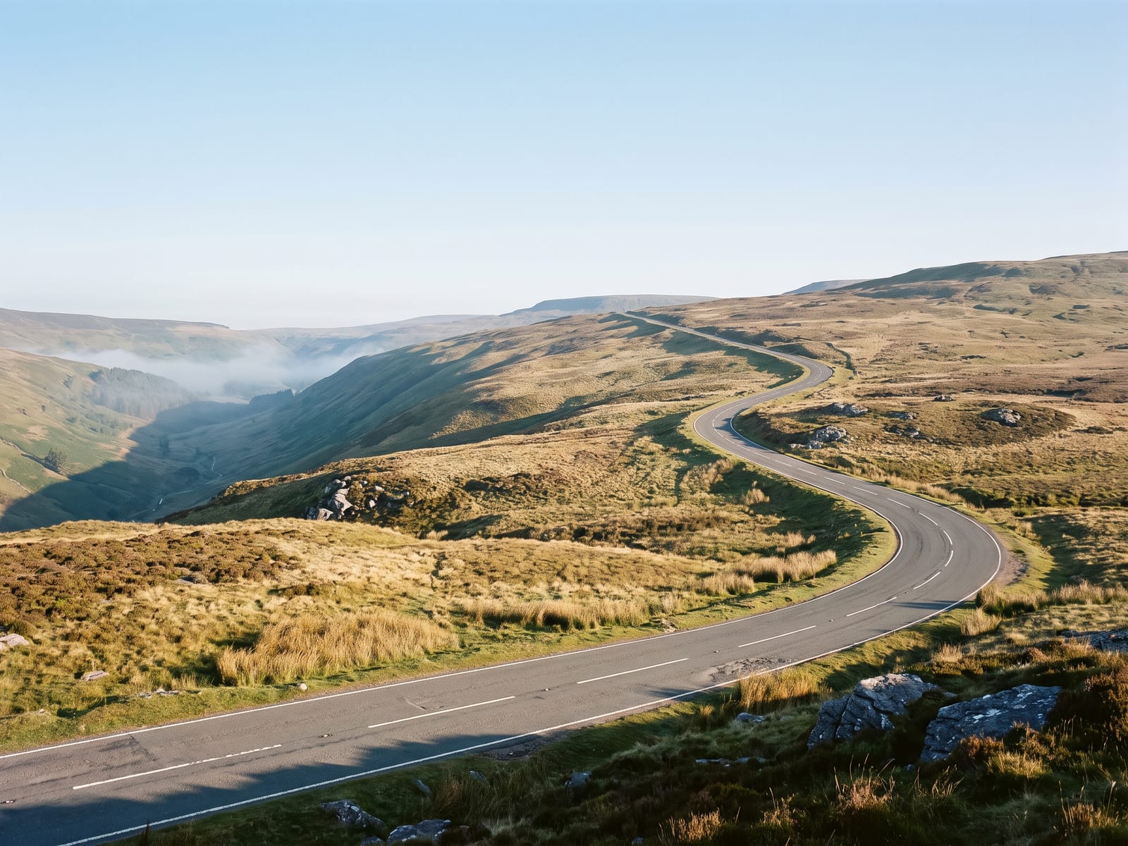 Near Llandovery: a smooth tarmac mountain road with sweeping bends climbing across bare, unfenced moorland in the Brecon Beacons, Wales