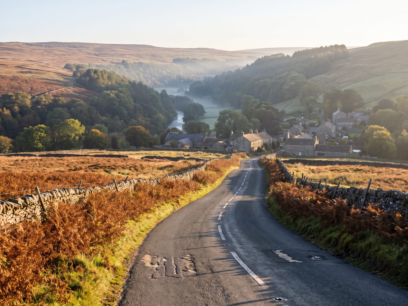 Near Pateley Bridge: a narrow tarmac road descending from open moor towards a wooded river valley in the Yorkshire Dales, dry-stone walls