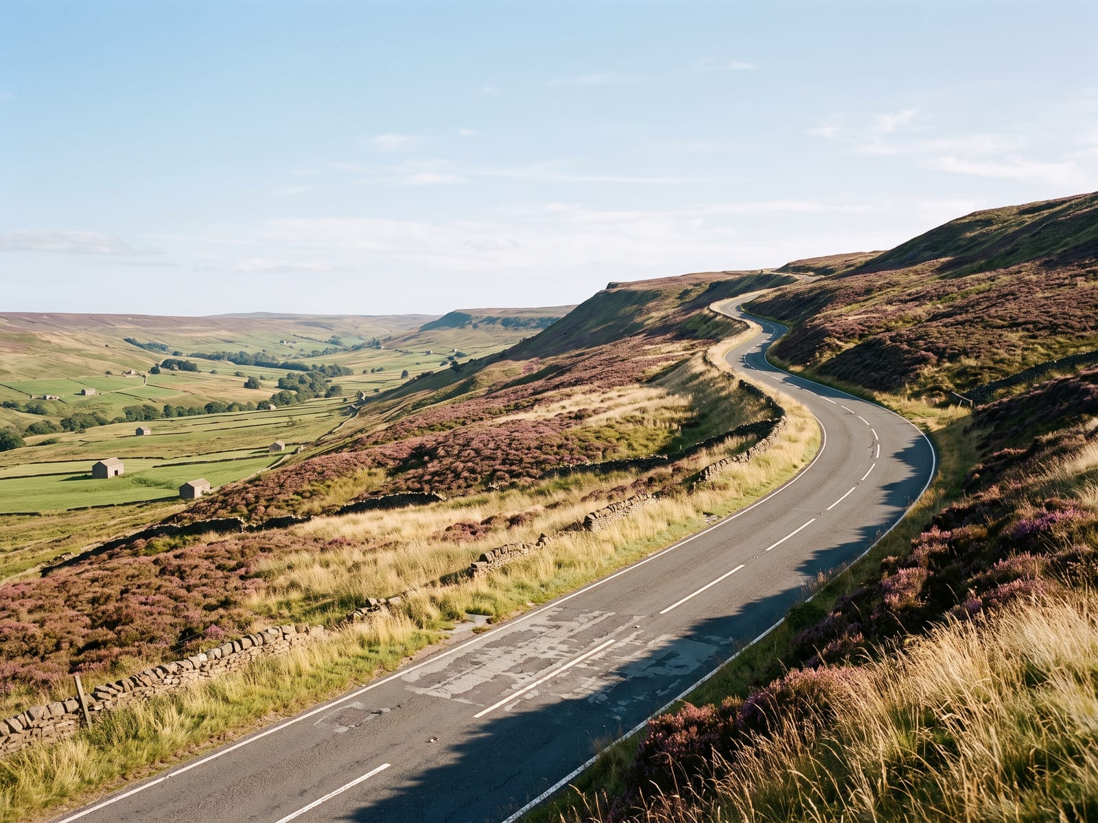Near Penrith: a two-lane road climbing in sweeping bends up a steep moorland escarpment above a broad green valley in northern