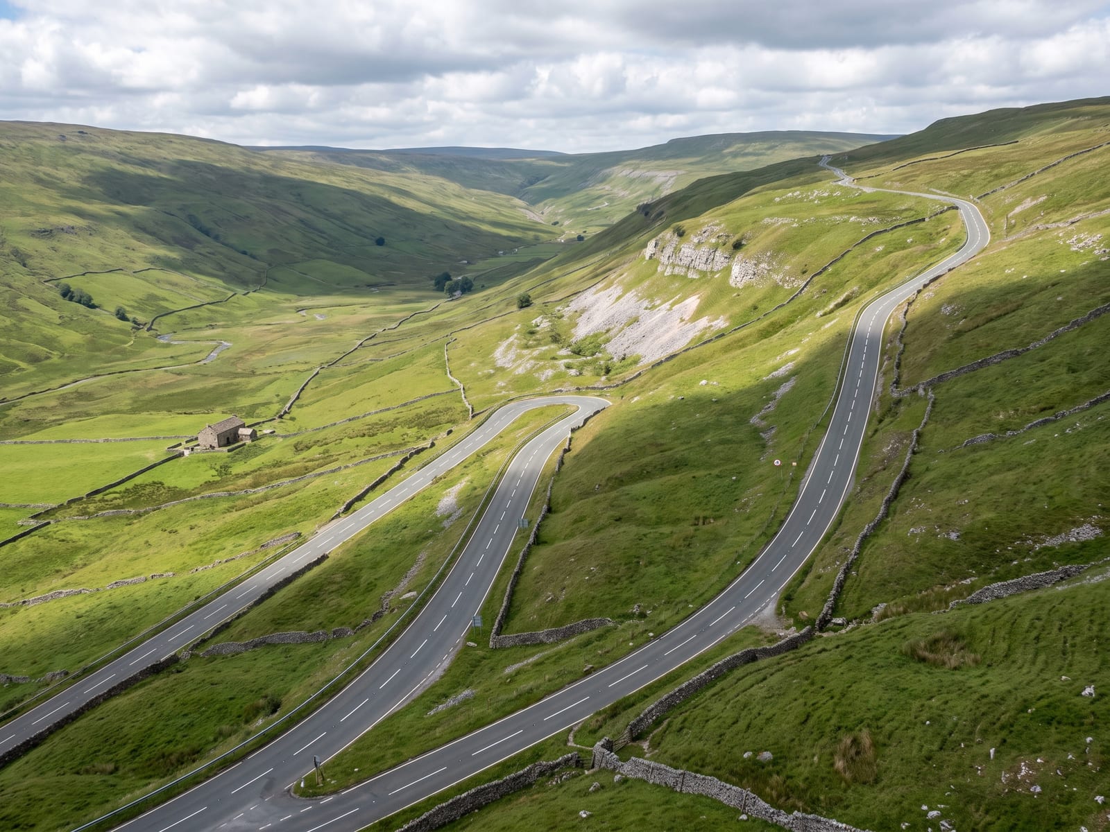 Near Skipton: a two-lane tarmac road climbing out of a broad glacial valley in the Yorkshire Dales